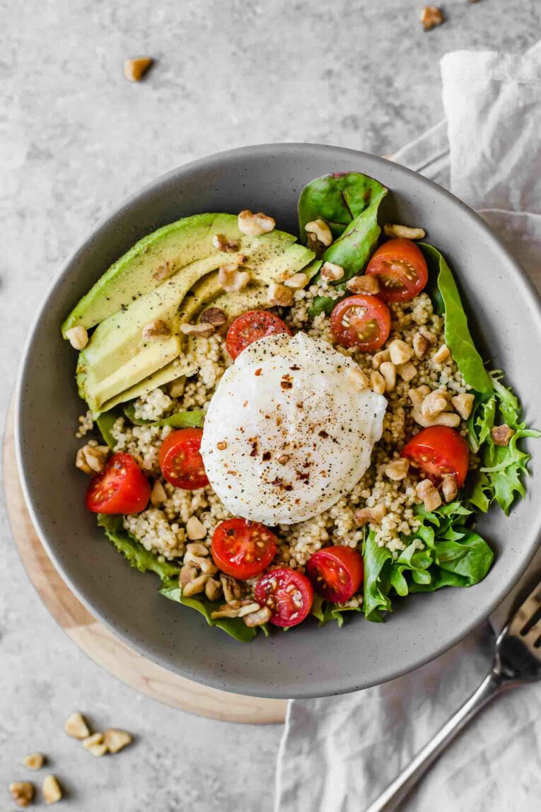 Top shot of breakfast salad with quinoa, avocado, tomatoes, and a poached egg.