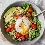 Close up of Poached Egg & Avocado Breakfast Salad in a grey bowl.
