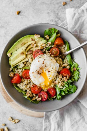 Close up of Poached Egg & Avocado Breakfast Salad in a grey bowl.