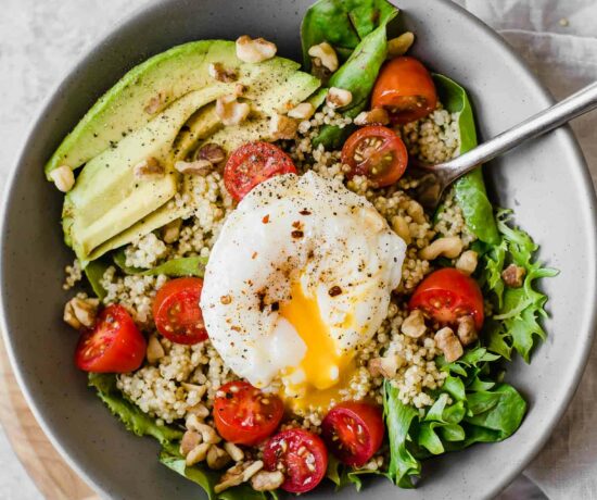 Close up of Poached Egg & Avocado Breakfast Salad in a grey bowl.