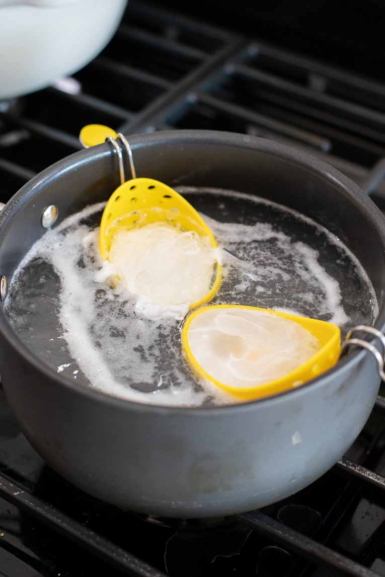 Eggs being poached in a pot of boiling water.