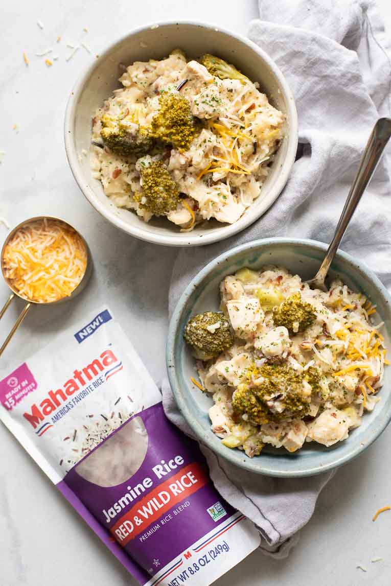 Two bowls of Crockpot Chicken and Rice next to cheese and Mahatma Rice.