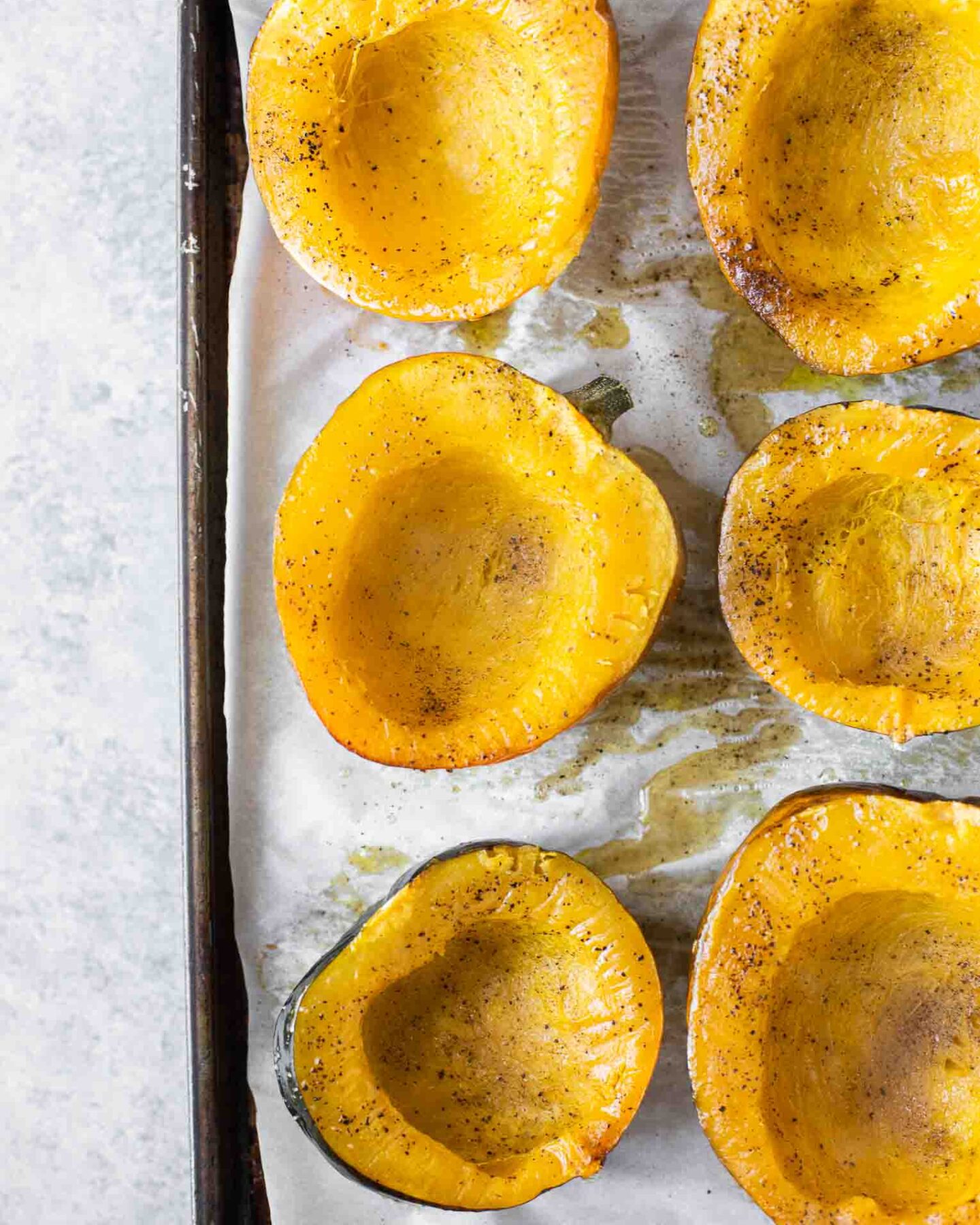 Roasted acorn squash on a baking sheet with parchment paper.