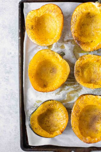 Roasted acorn squash on a baking sheet with parchment paper.