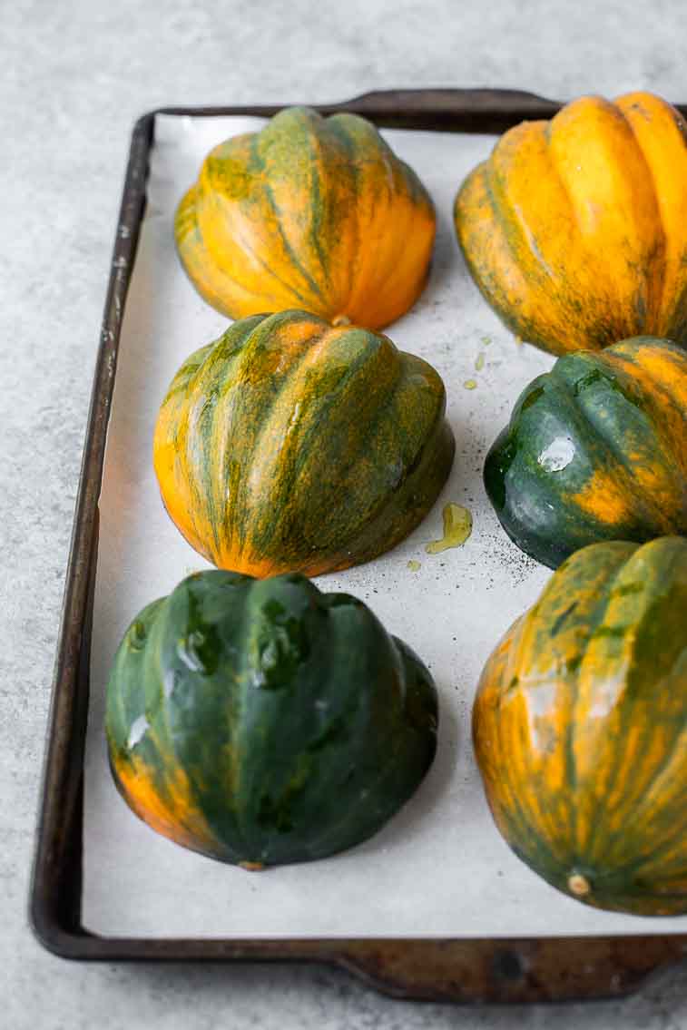 Close up of raw acorn squash on a baking sheet.