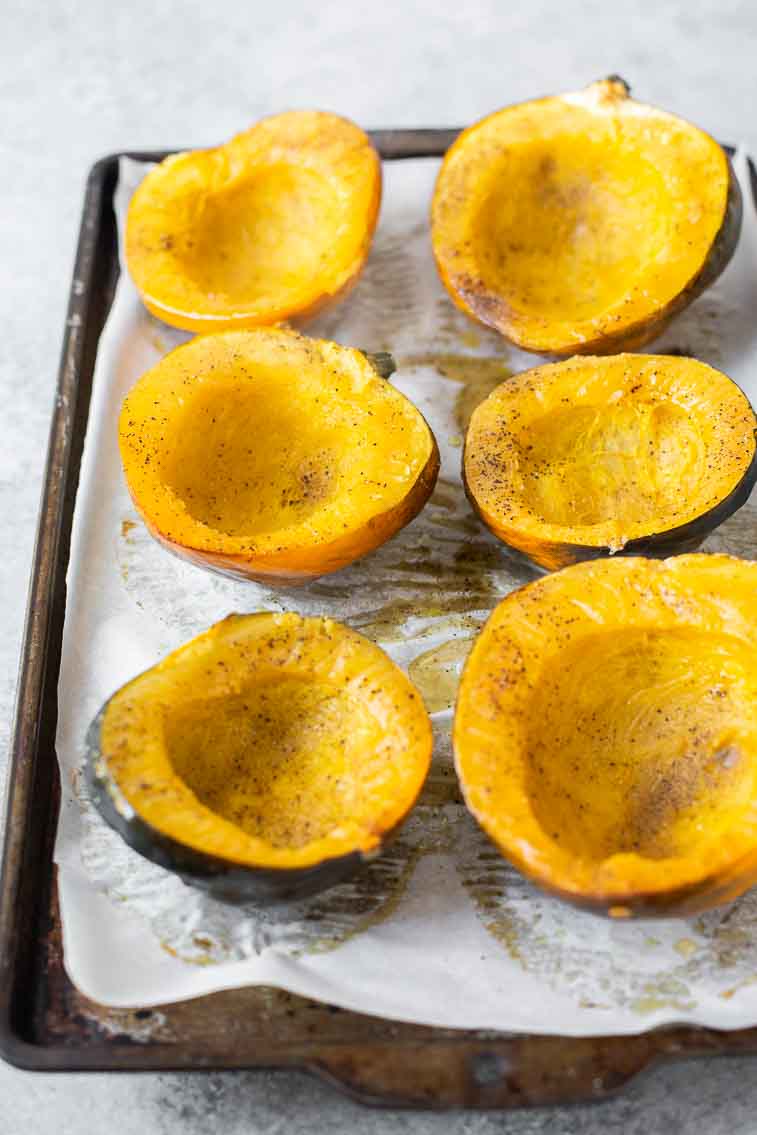Angled shot of roasted acorn squash on a baking sheet.
