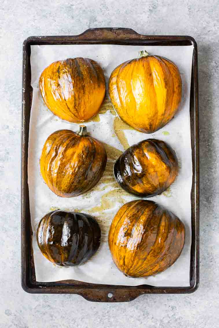 Roasted acorn squash face down on a baking sheet.