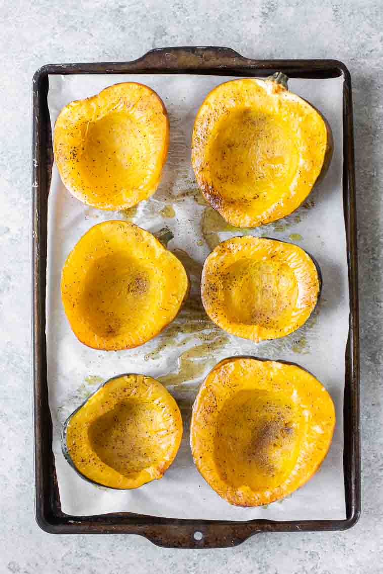 Top shot of roasted acorn squash face up on a baking sheet.
