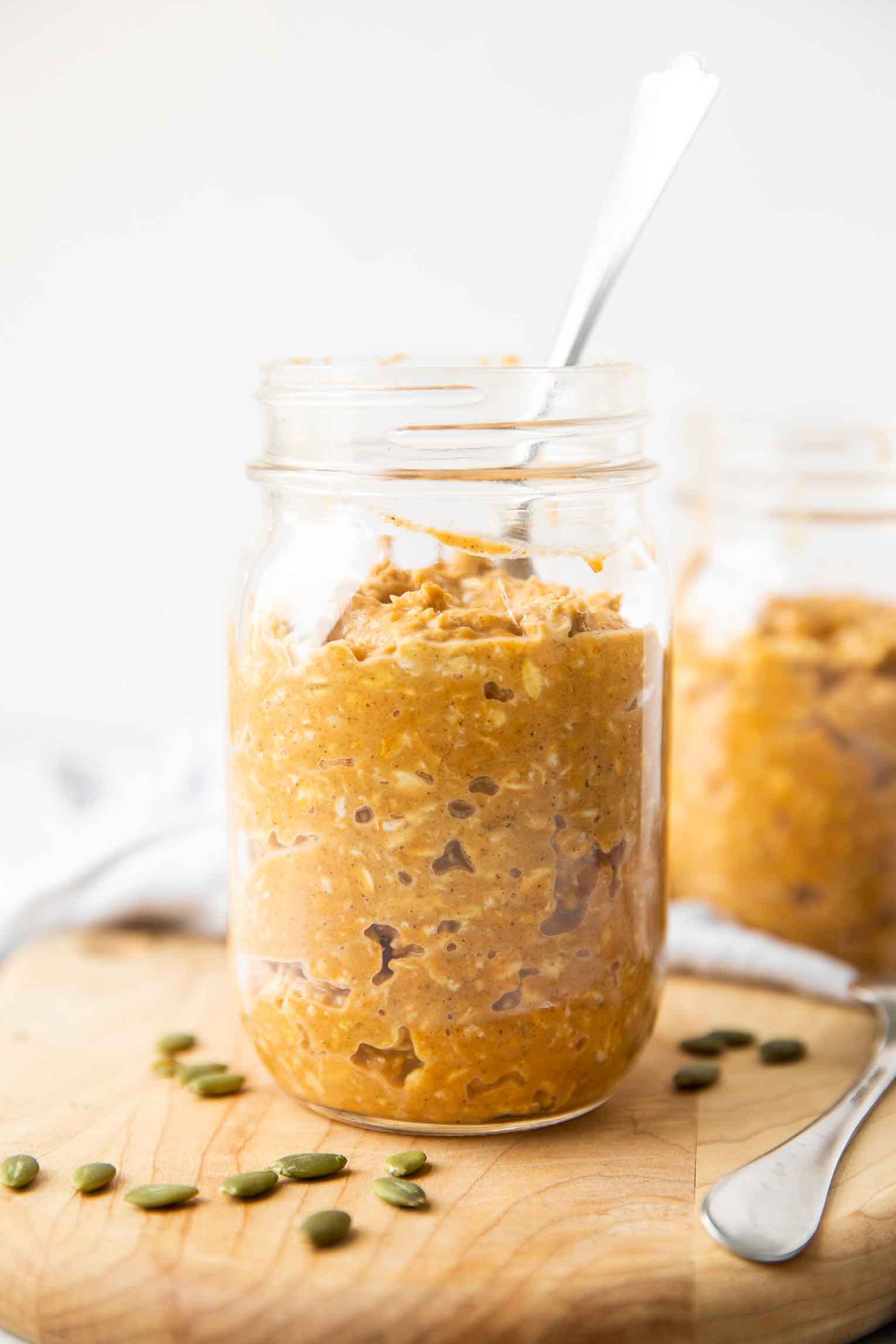 Close up of pumpkin overnight oats in a mason jar with a spoon.
