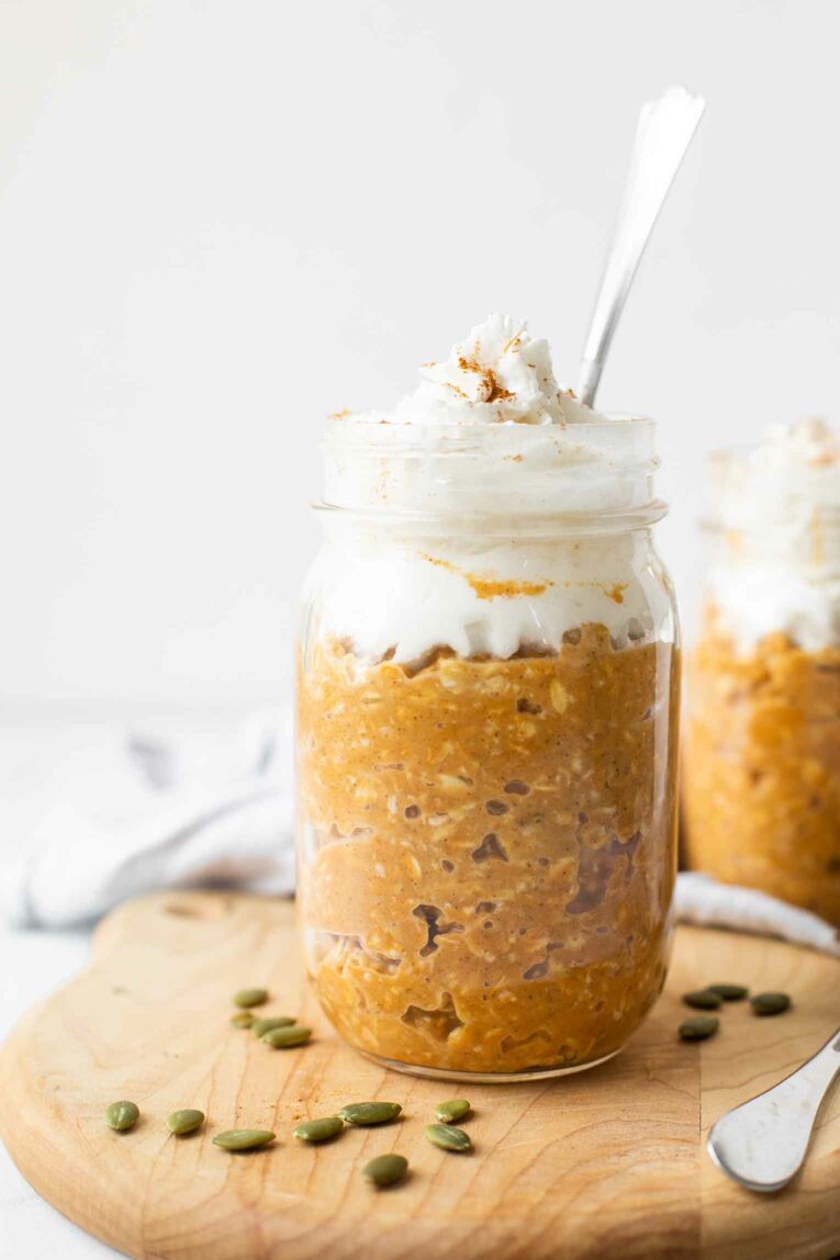 Pumpkin pie overnight oats in a mason jar topped with coconut whipped cream.