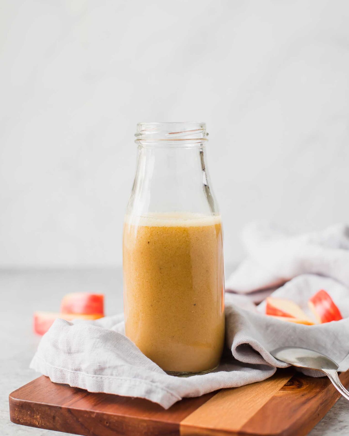 Apple cider vinaigrette in a glass bottle on a cutting board.