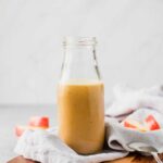 Apple cider vinaigrette in a glass bottle on a cutting board.