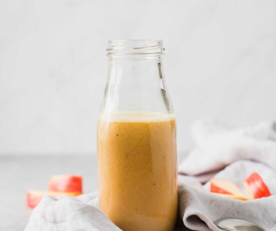 Apple cider vinaigrette in a glass bottle on a cutting board.