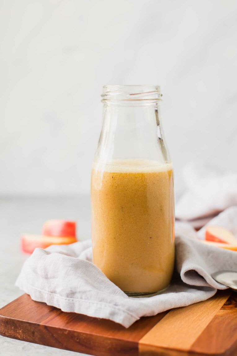 Across shot of apple cider vinaigrette on a wood cutting board.