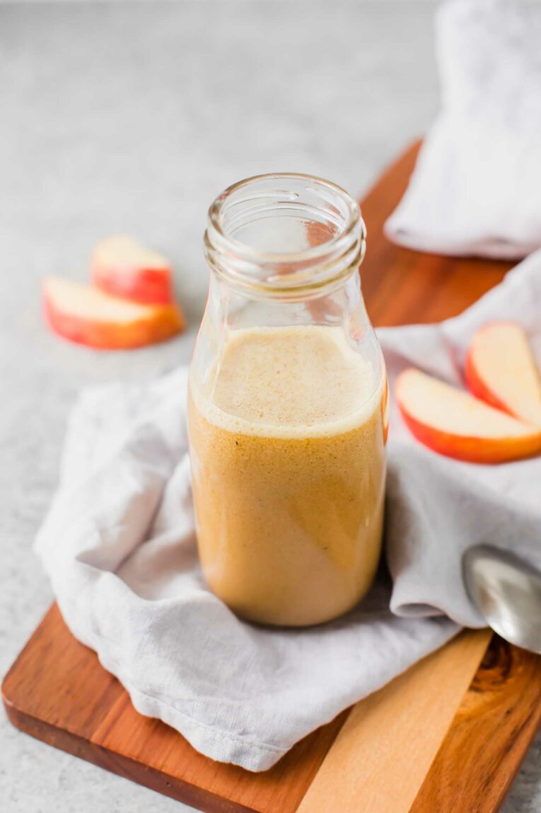 Angled shot of apple cider vinaigrette in a glass bottle.