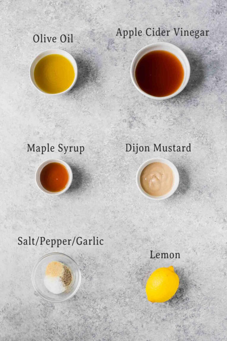 Ingredients for apple cider vinaigrette on a grey background.