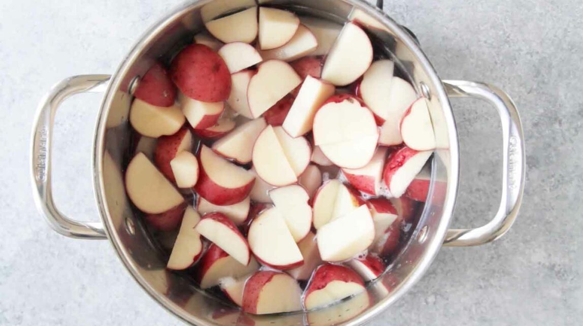 Red potatoes boiling in a pot of water.