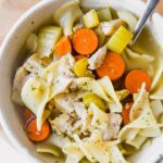 Top shot of easy turkey noodle soup in a white bowl with a spoon.