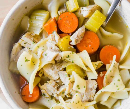 Top shot of easy turkey noodle soup in a white bowl with a spoon.