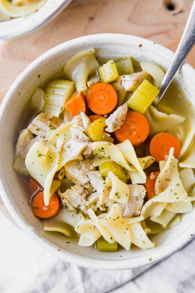 Top shot of easy turkey noodle soup in a white bowl with a spoon.