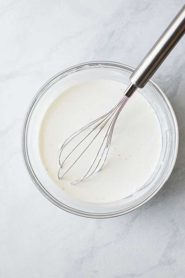 Creamy sauce being whisked together in a mixing bowl.