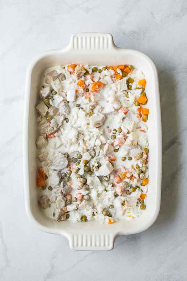 Rice, peas, carrots, turkey, and yogurt sauce in a casserole dish.