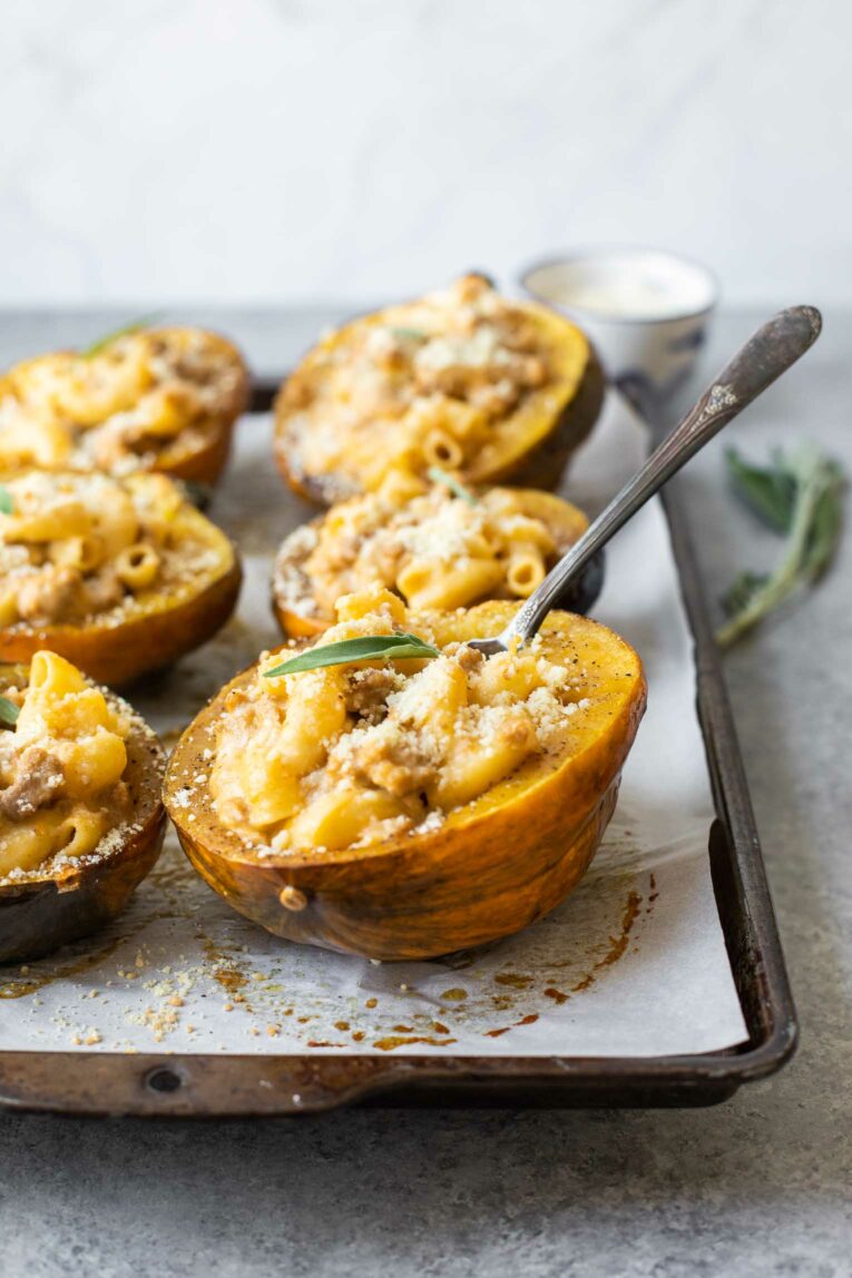 Fork taking bite out of mac and cheese stuffed acorn squash.