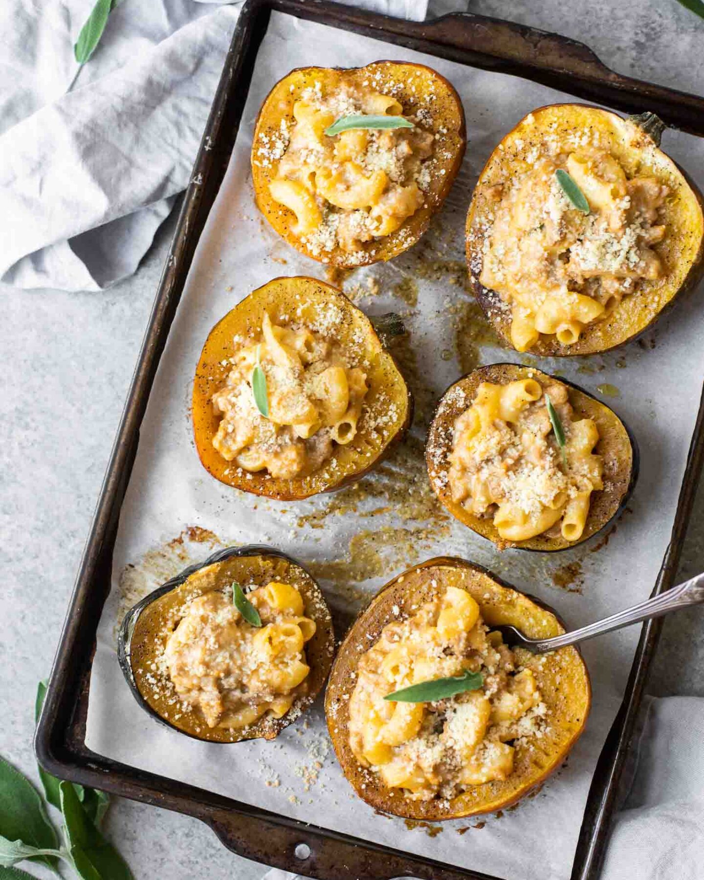Mac and cheese stuffed acorn squash on a baking sheet.