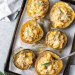 Mac and cheese stuffed acorn squash on a baking sheet.