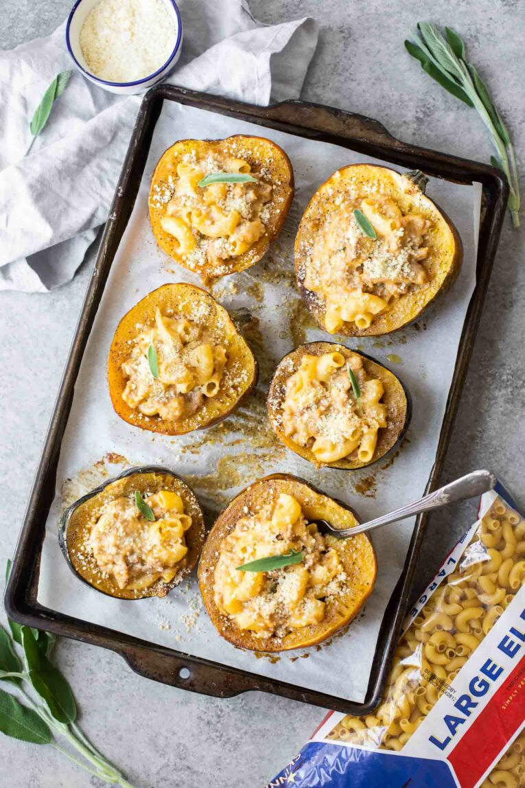 Angled shot of mac and cheese stuffed acorn squash with sage.