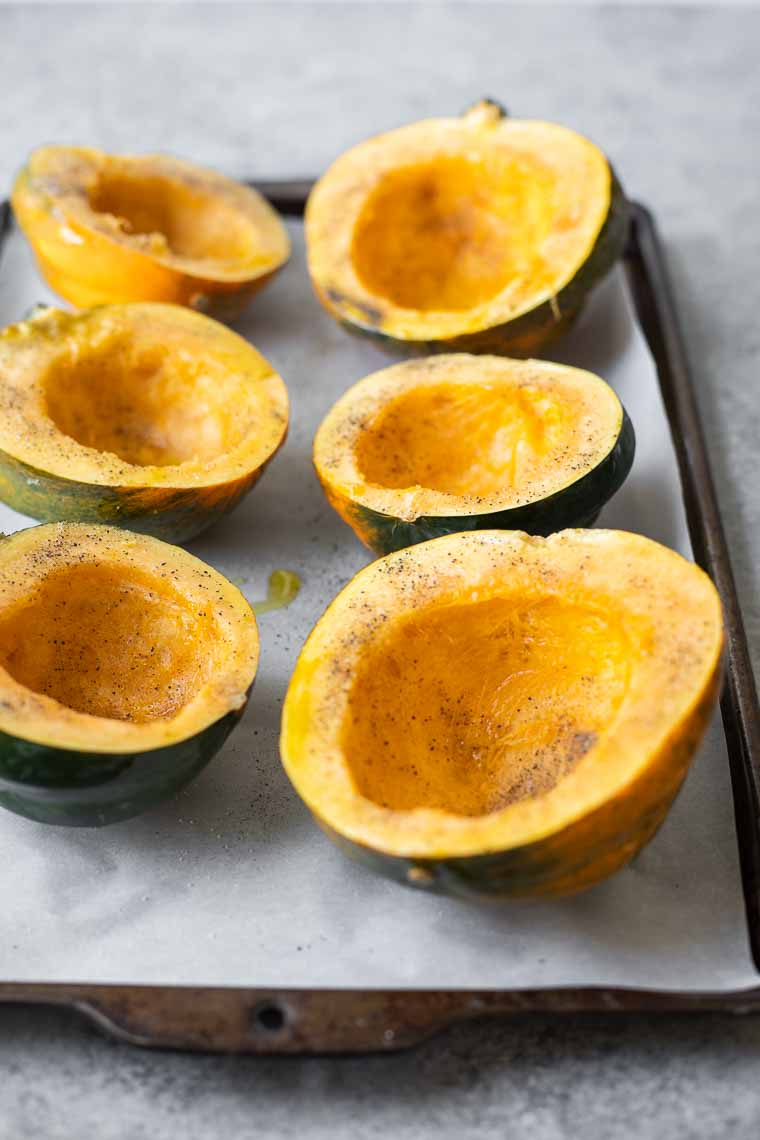 Acorn squash on a baking sheet cut into halves.