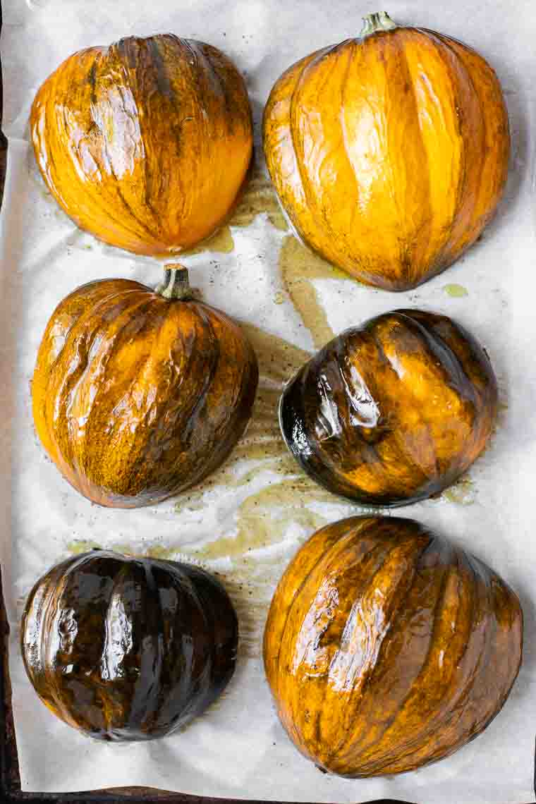 Roasted acorn squash facedown on a baking sheet lined with parchment paper.