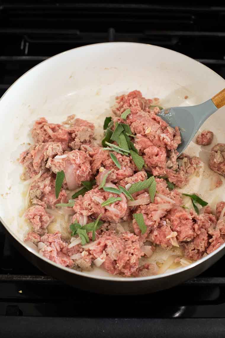 Ground turkey and sage cooking in a skillet.