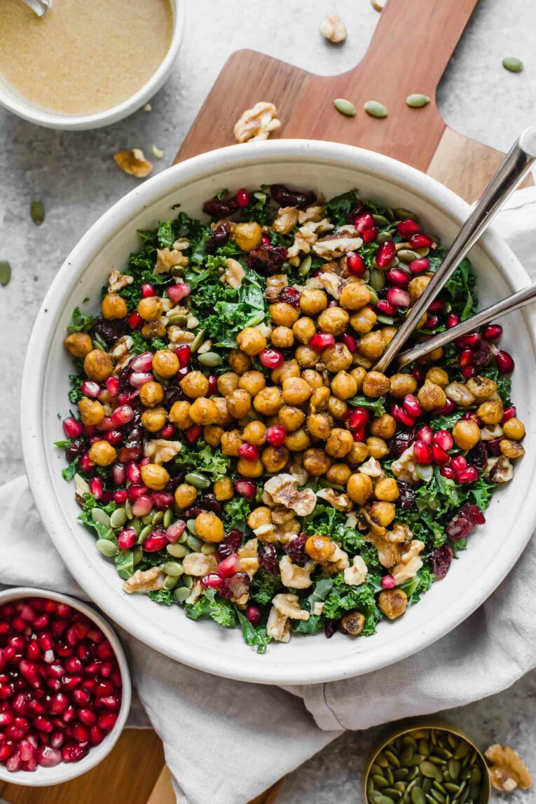 Top shot of roasted chickpea fall salad in a white bowl on a wood cutting board.