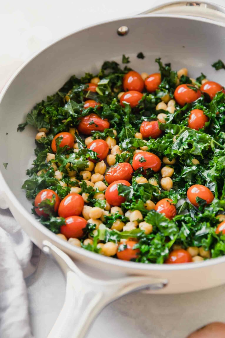 Close up on non-toxic cookware with kale, chickpeas, and tomatoes.