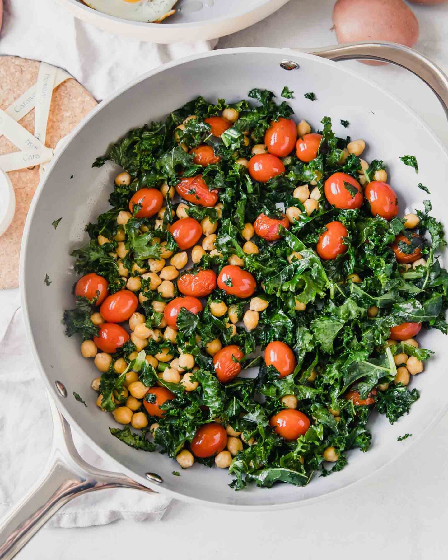 Top shot of non-stick non-toxic cookware with eggs, kale, tomatoes, and chickpeas.