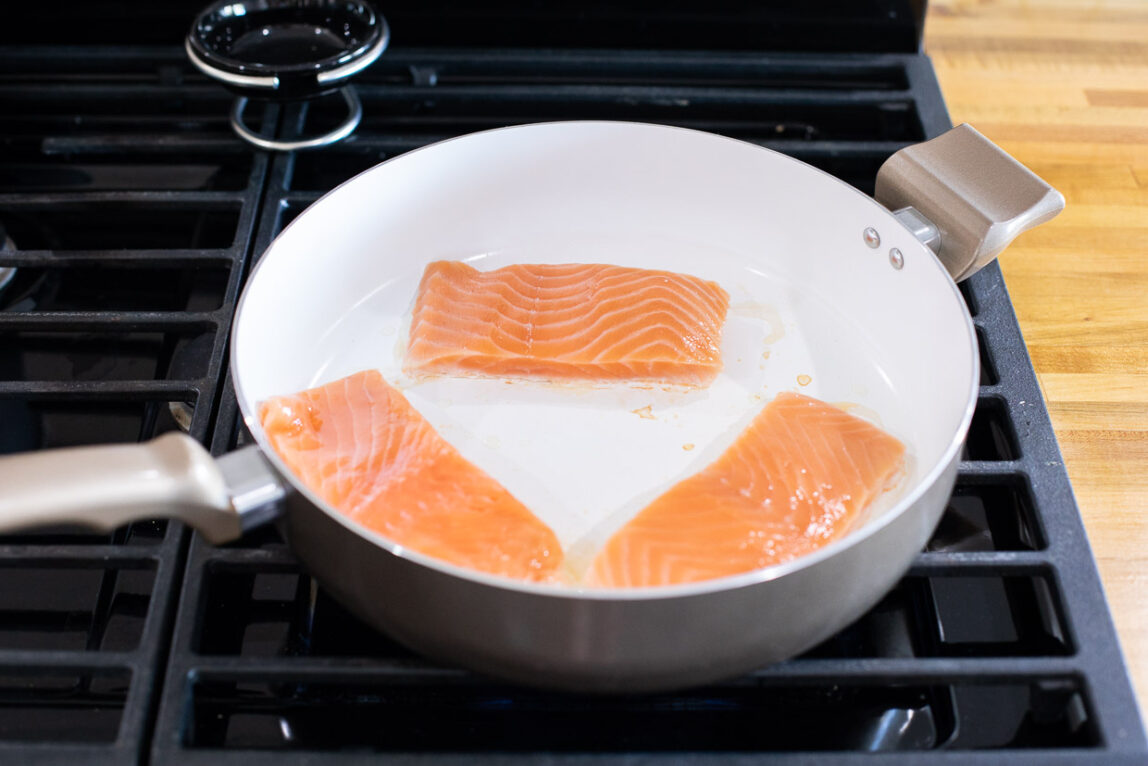 Skinless salmon being pan-fried.