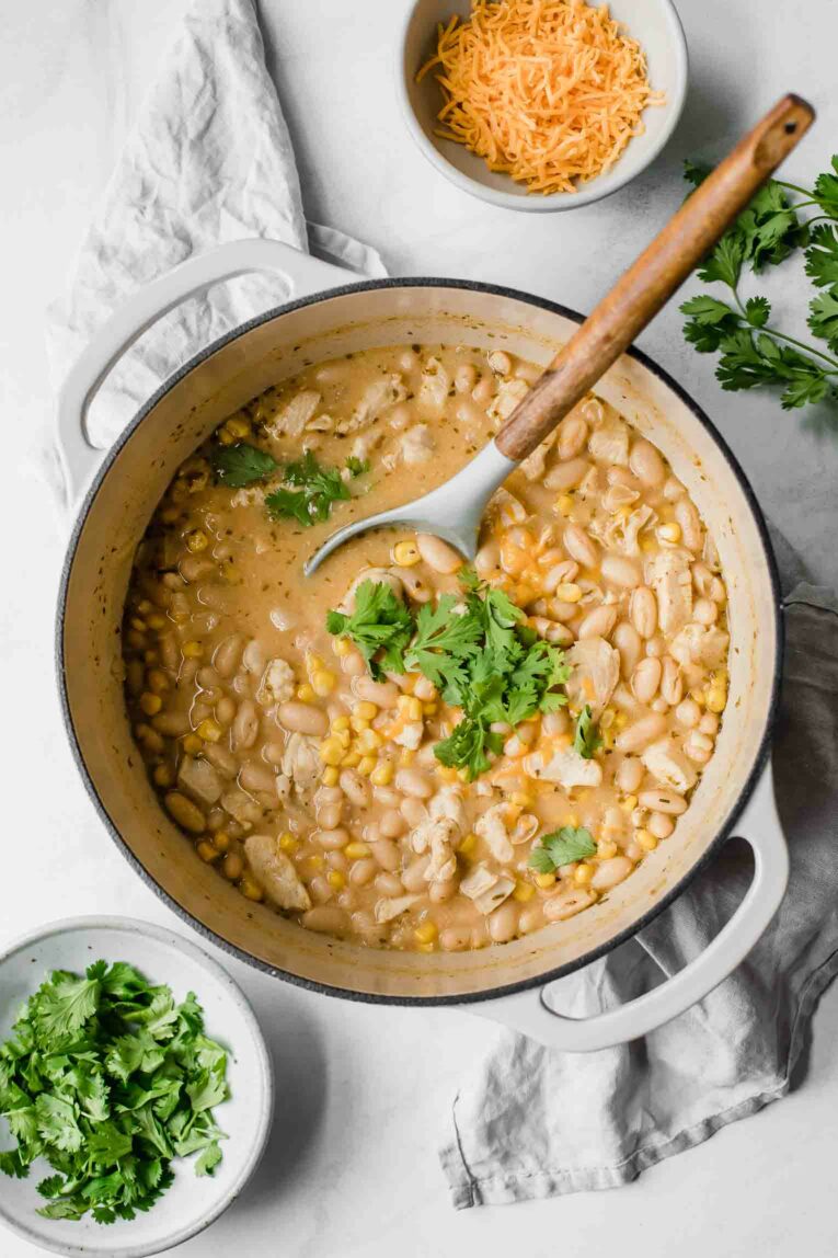 Top shot Creamy White Chicken Chili in a dutch oven with a serving spoon.