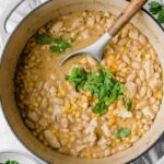 Creamy white chicken chili topped with cilantro and cheese in a dutch oven.