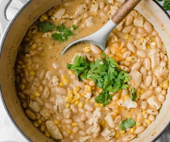 Creamy white chicken chili topped with cilantro and cheese in a dutch oven.