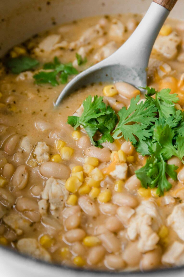 Angled shot close up of white chicken chili in a dutch oven.