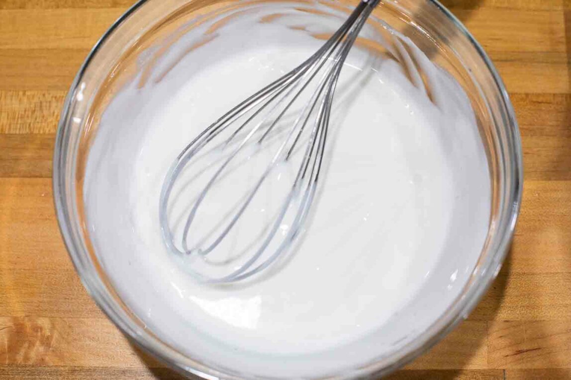 Plain yogurt being whisked in a bowl.