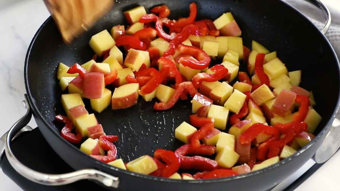 Potatoes and peppers cooking in a skillet.