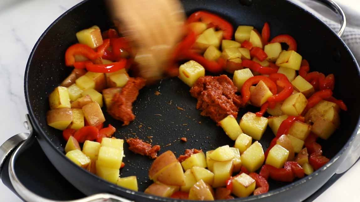 Potatoes and peppers cooking with a curry paste.