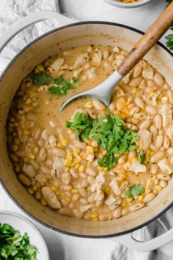 Creamy white chicken chili topped with cilantro and cheese in a dutch oven.