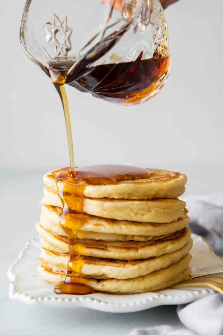 Maple syrup pouring over yogurt pancakes stack.