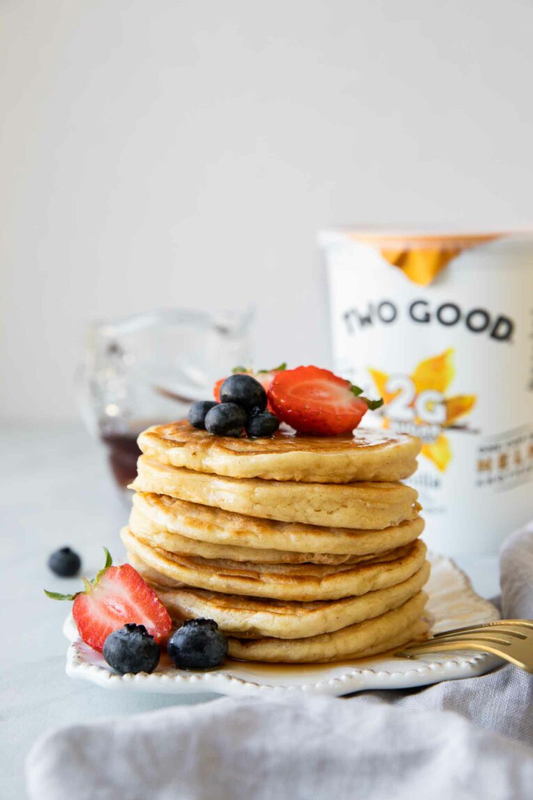 Yogurt pancakes stack with Two Good Vanilla Greek Yogurt in the background.