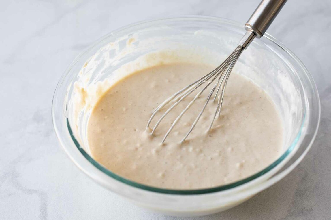 Pancake batter in a glass bowl with a whisk.