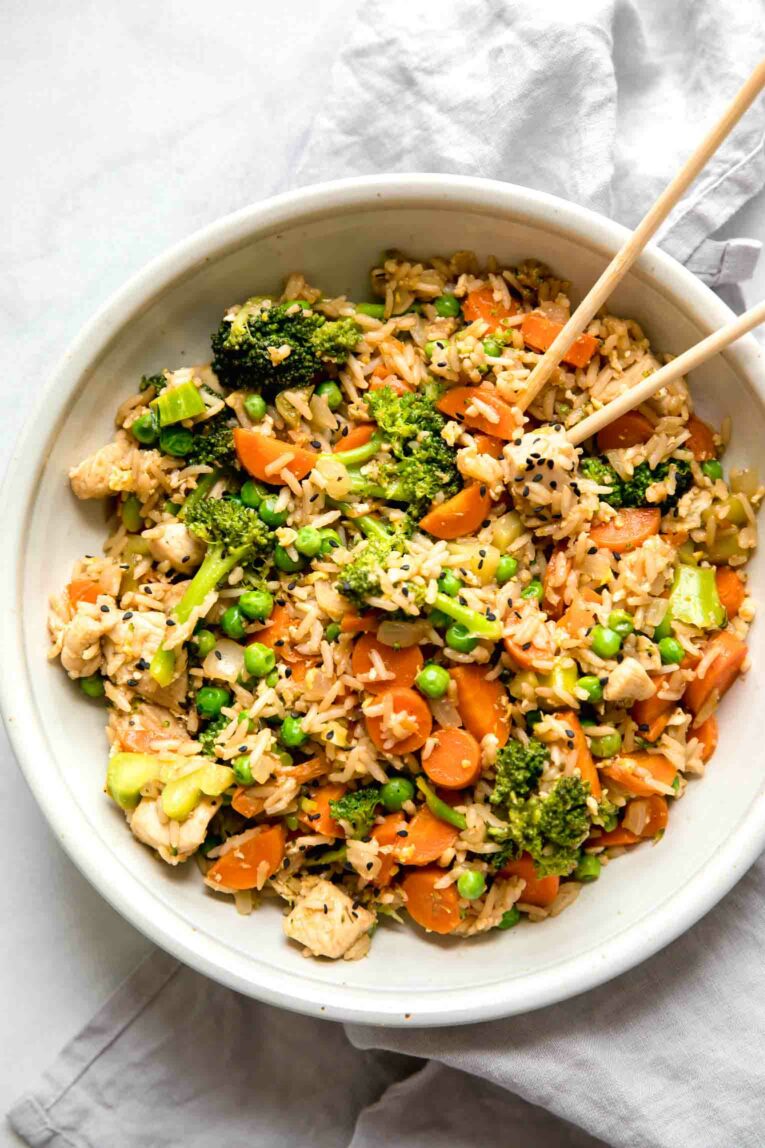 Top shot of chicken fried rice in a bowl with chopsticks.