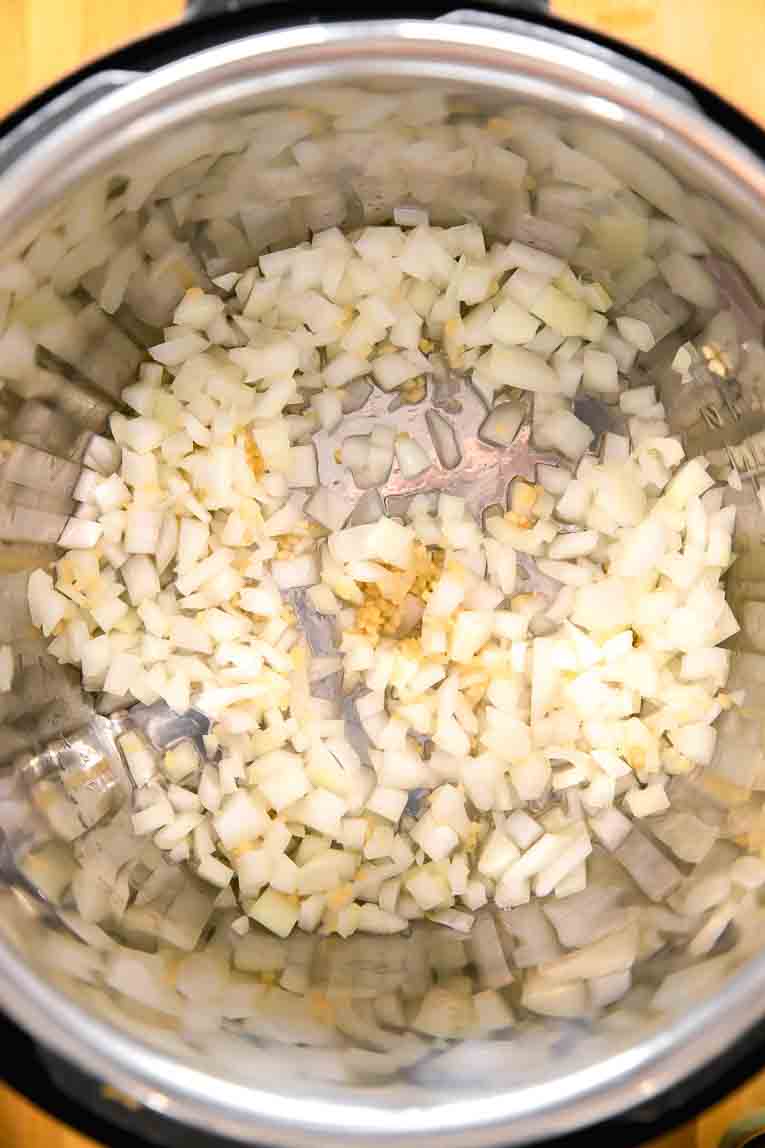Onions and garlic being sautéed in an Instant Pot.